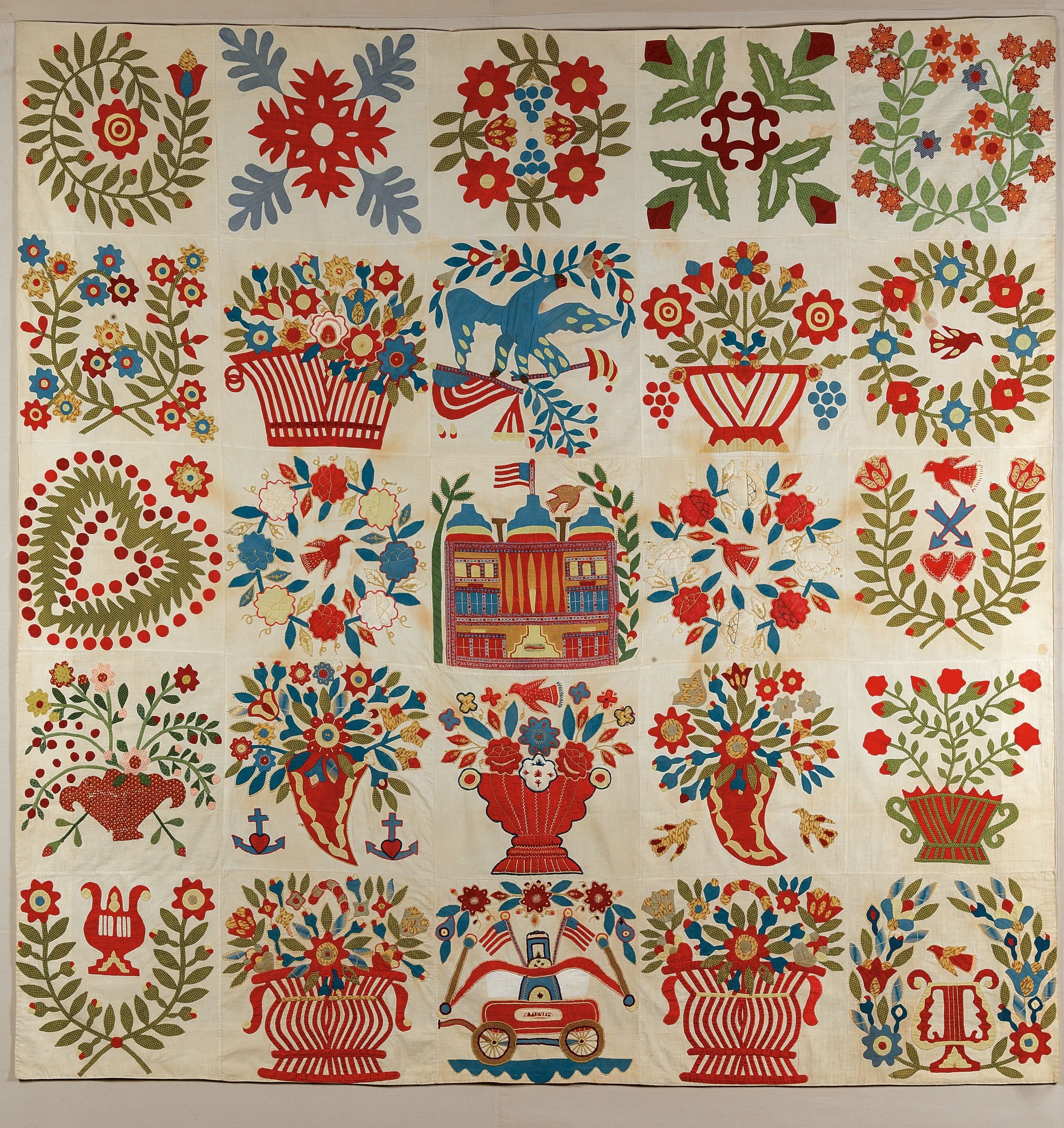 Quilt with 25 embroidered patches featuring floral, bird, heart, and symbolic folk-art motifs.
