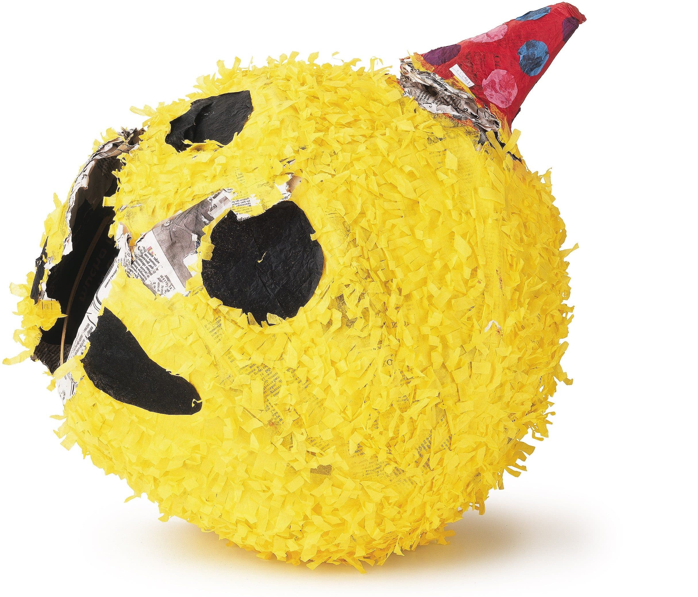 Yellow emoji face piñata with a red party hat and visible tears in the paper covering.