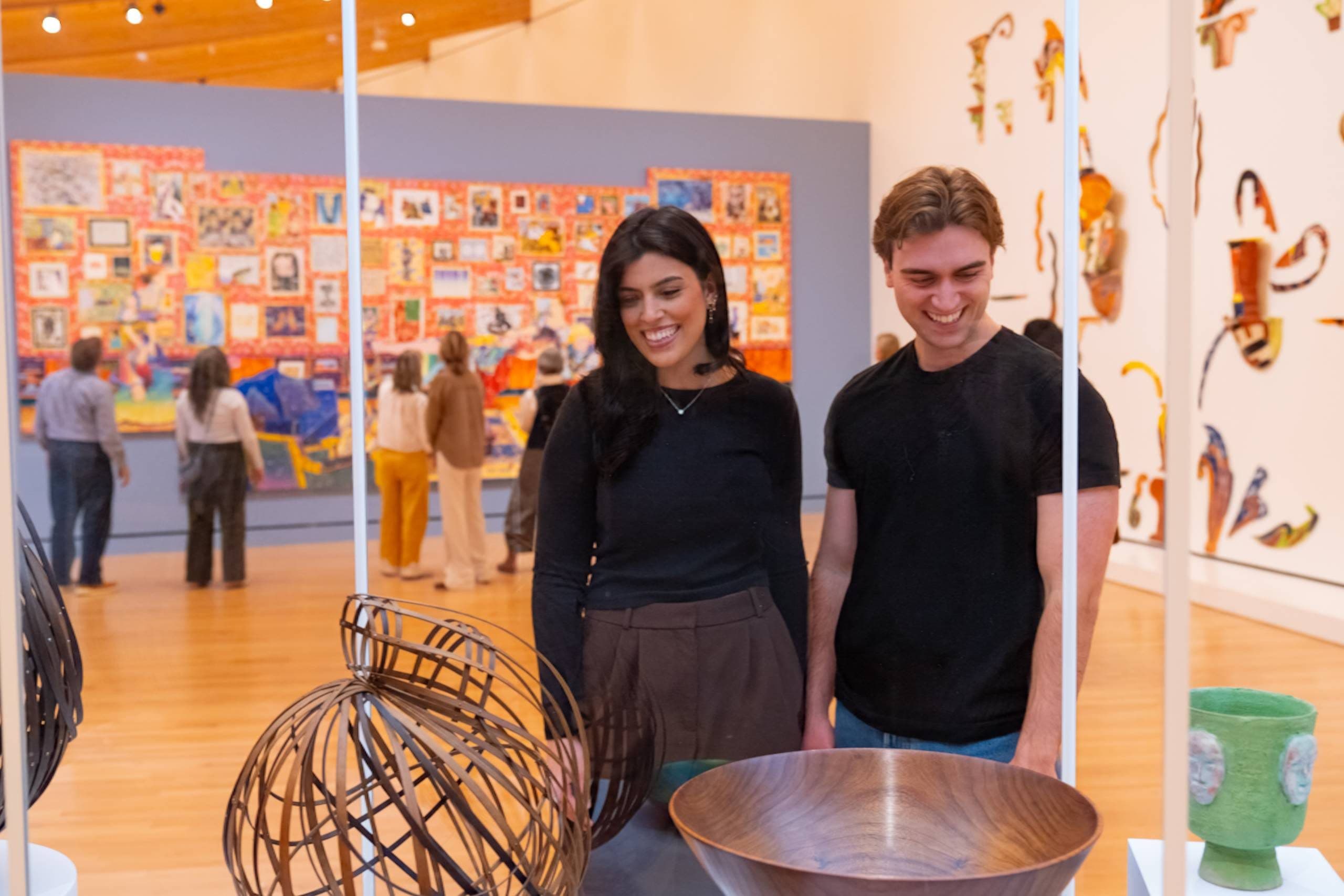 Museum visitors viewing sculptures and a colorful collage